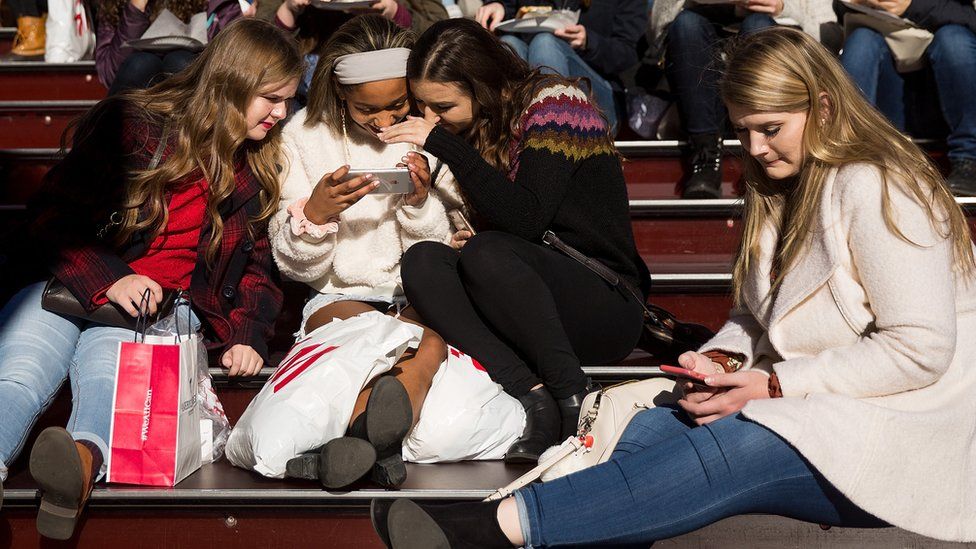 Teenagers look at their mobile phones