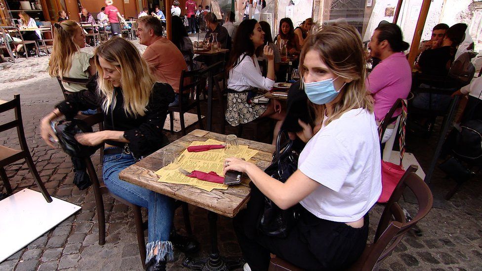 Busy restaurant with mask-wearer and screen