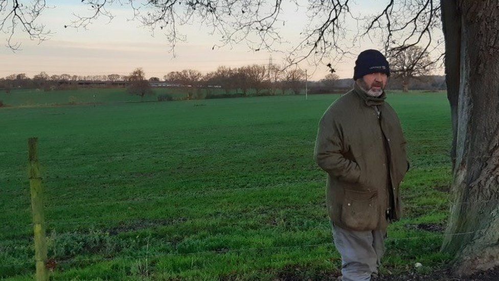 Farmer Andrew Lake standing next to an empty green field
