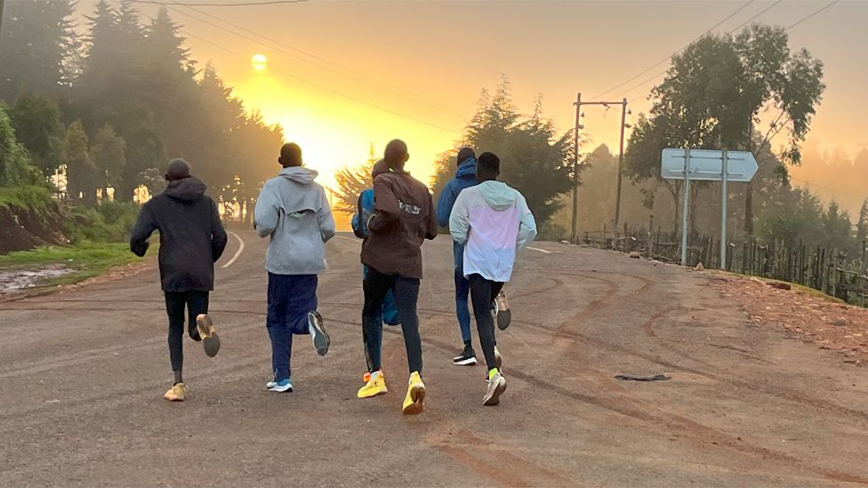 Runners training in western Kenya along a road heading into the sun