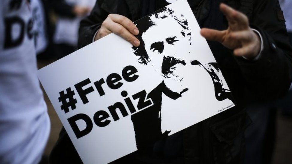 A man holds a poster with the slogan "#FREEDENIZ" during a protest in front of the Turkish embassy in Berlin, on 28 February 2017
