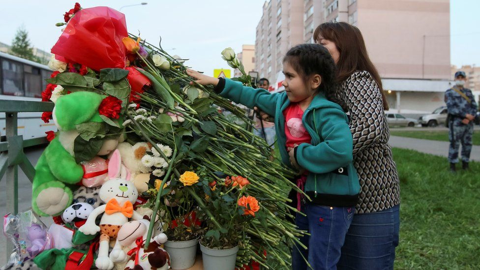 Люди возлагают цветы к импровизированному мемориалу жертвам смертельного обстрела в школе № 175 Казани, Россия, 11 мая 2021 г.