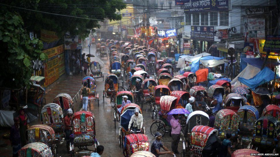Rickshaw pullers await passengers during the falling of monsoon rains