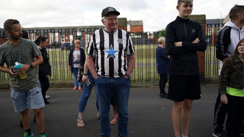 An elderly man in Ashington wears an old Newcastle United shirt and cap