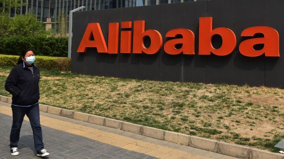 Woman walks past Alibaba sign