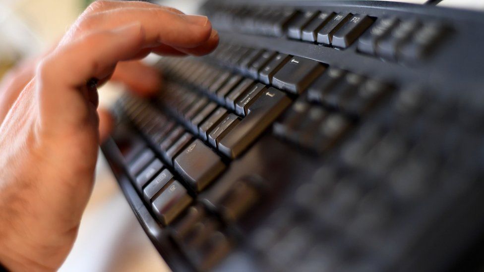 Man's hands typing on a computer keyboard