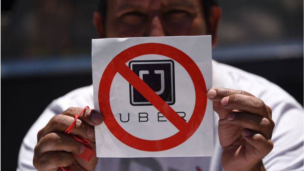 A taxi driver in Guatemala holds a "No Uber" sign