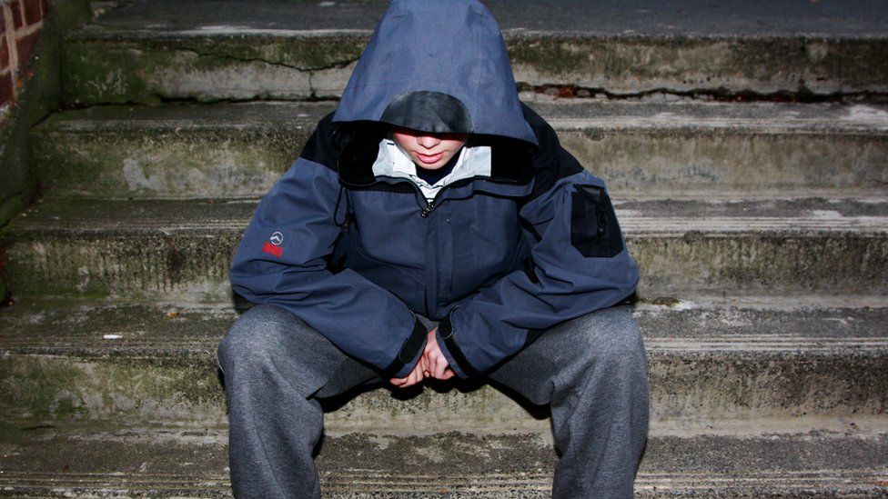 A teenage boy wearing a hooded jacket at night