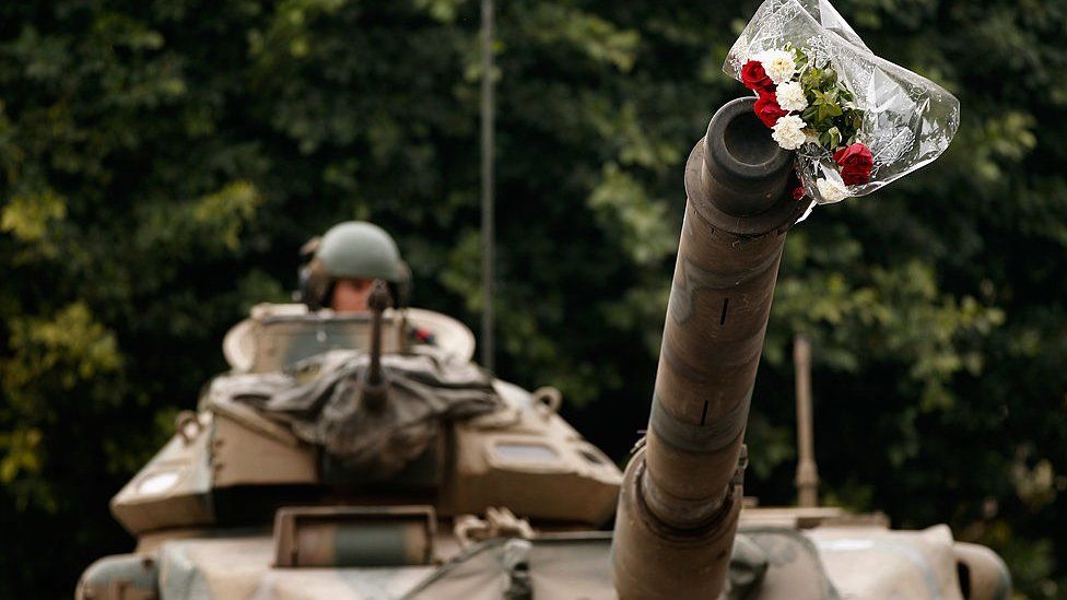 Цветы украшают ствол армейского танка на авеню Бургиба в Тунисе во время восстания в январе 2011 года