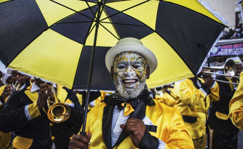 A man with face paint and matching black-and-yellow umbrella