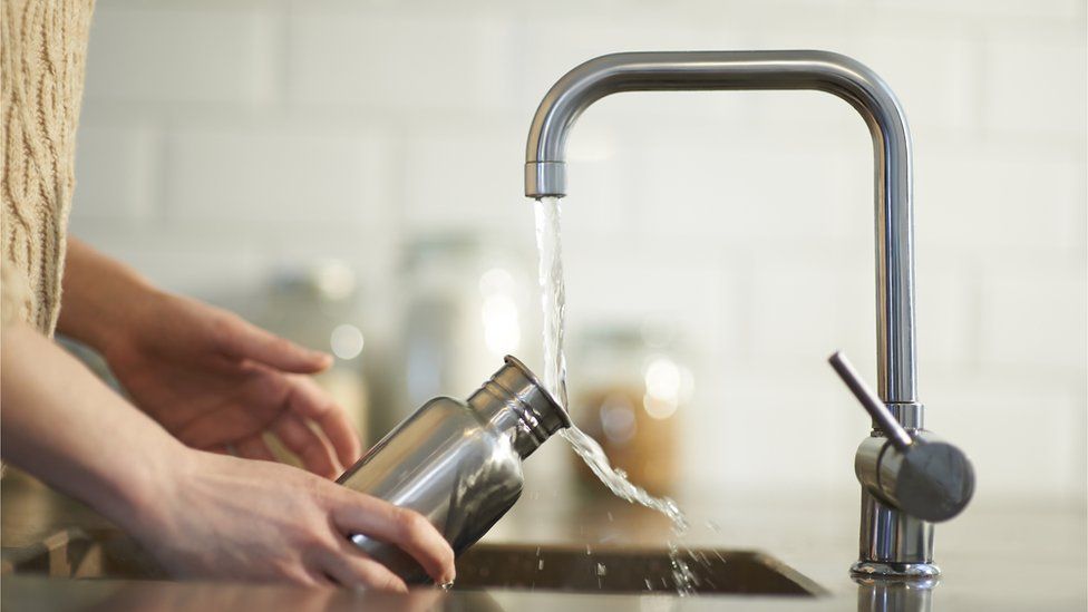Cleaning a plastic free reusable water bottle in kitchen sink. - stock photo