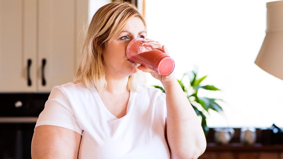 A woman on a diet drinking a smoothie (posed model)