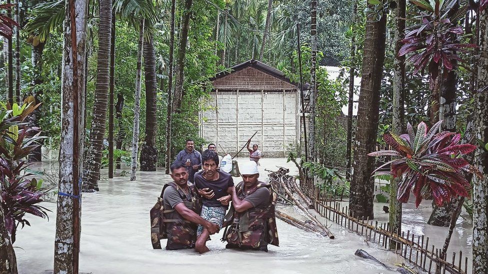 Army personnel wade through flood waters to reach stranded persons