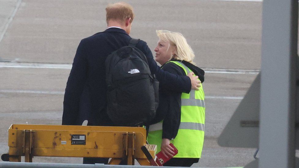 Prince Harry placing his arm around worker a Aberdeen airport