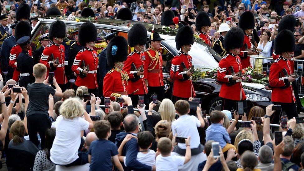 Crowds watch the procession of the Queen's coffin
