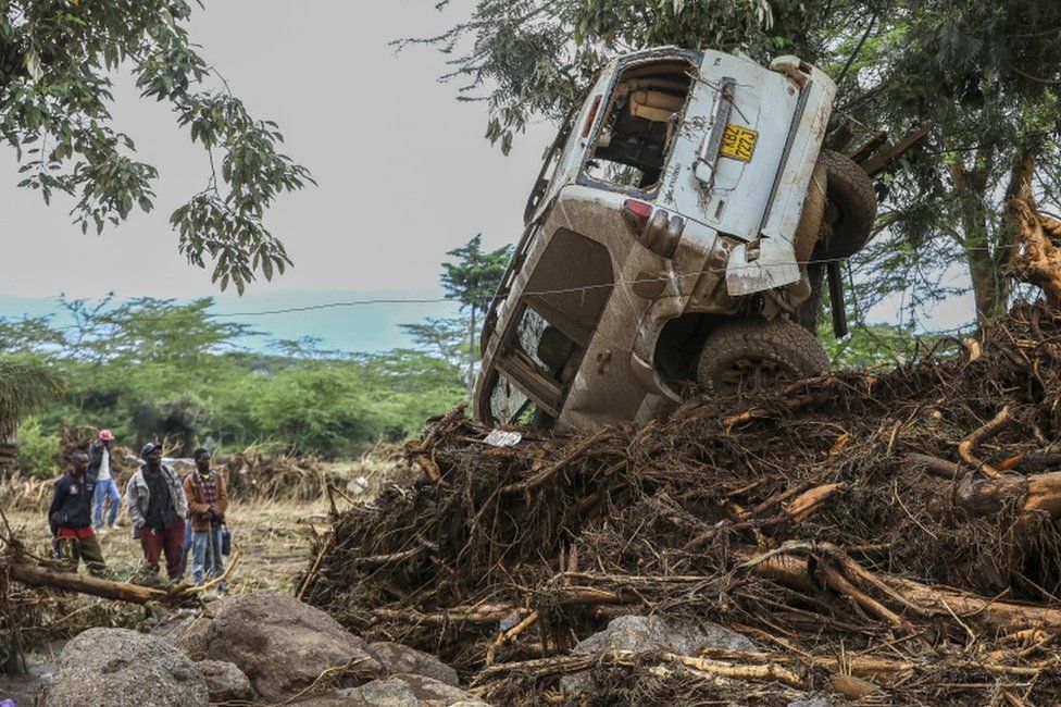 People look at a damaged car after flash floods in Mai Mahiu, in the Rift Valley region of Naivasha, Kenya, on 30 April.