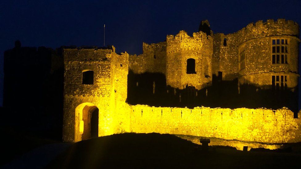 Carew Castle illuminated in yellow