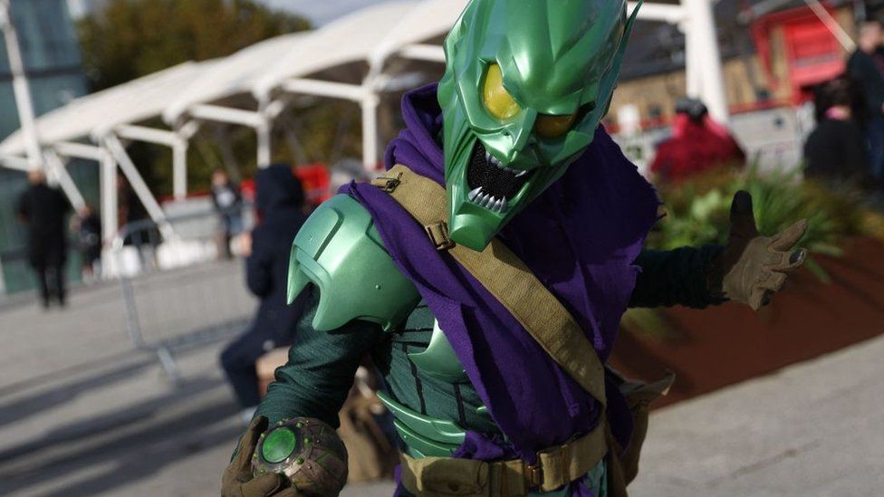 A person dressed as the Green Goblin holds a scary pose outside the event