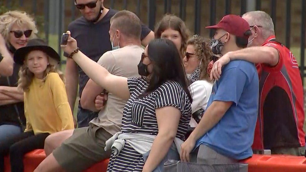 People take selfies over the border barricade