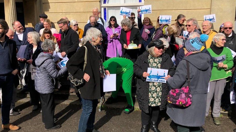 A crowd of people holding "free our croc" signs