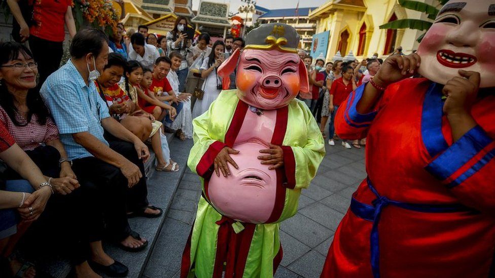 Performers in costumes of a pig (C) and other traditional Chinese characters entertain tourists at a temple during a performance to celebrate the Lunar New Year, or Spring Festival, in Chinatown in Bangkok