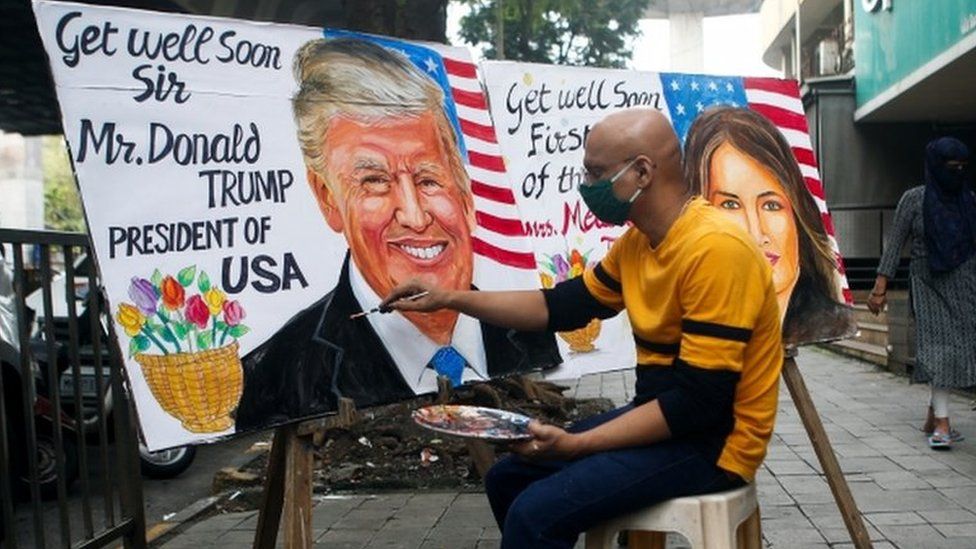 A man paints a mural of U.S. President Donald Trump and first lady Melania after they tested positive for the coronavirus on a street in Mumbai, India