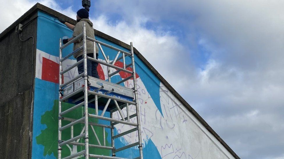 man standing on scaffolding painting building