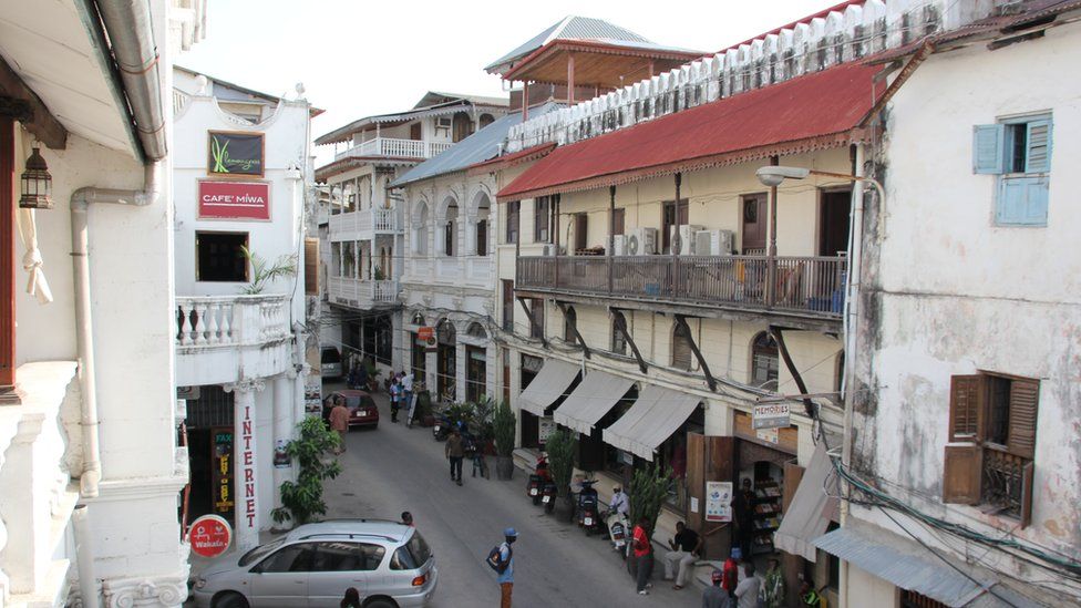 People walk in the street close to Freddie Mercury House in Stone Town, the historic part of Zanzibar City