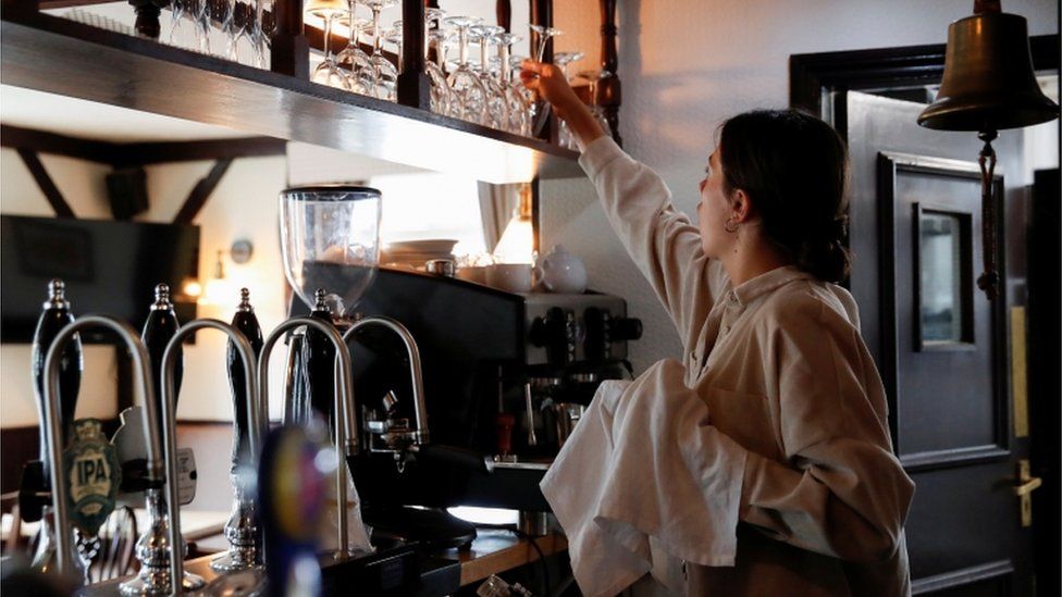 A woman cleaning wine glasses behind a bar