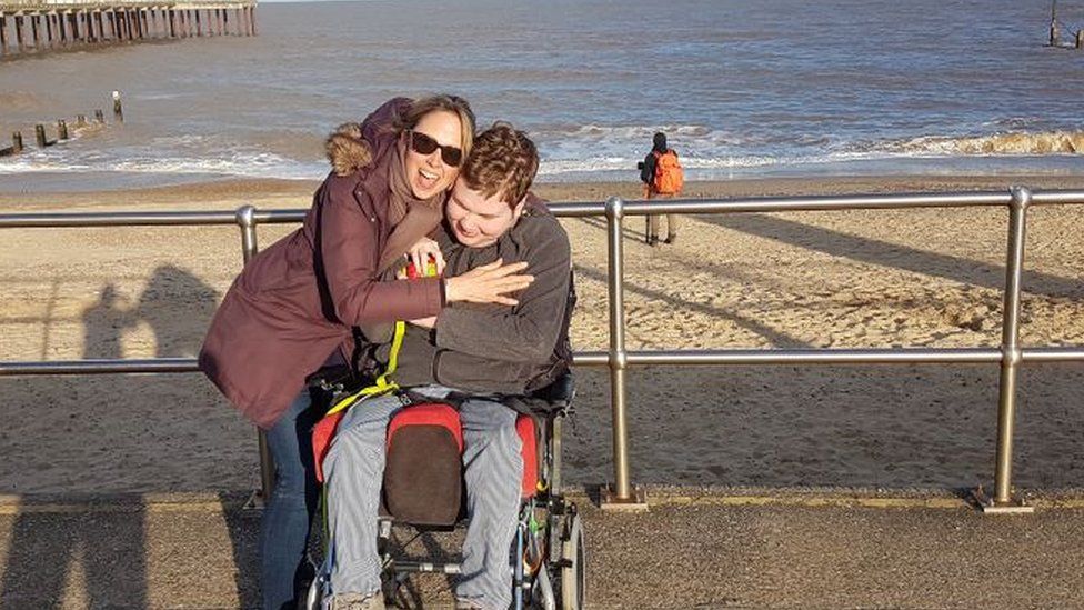 Tamsin Olney and Oscar at the beach. Oscar is in a wheelchair.