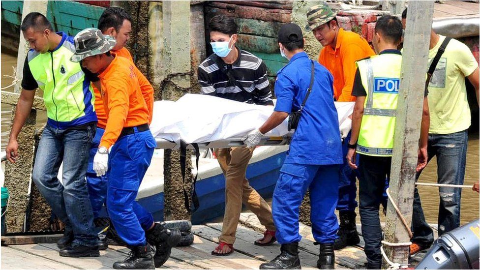 Rescuers carry a body recovered from a capsized boat believed to be carrying illegal migrants, at a jetty in Hutan Melintang