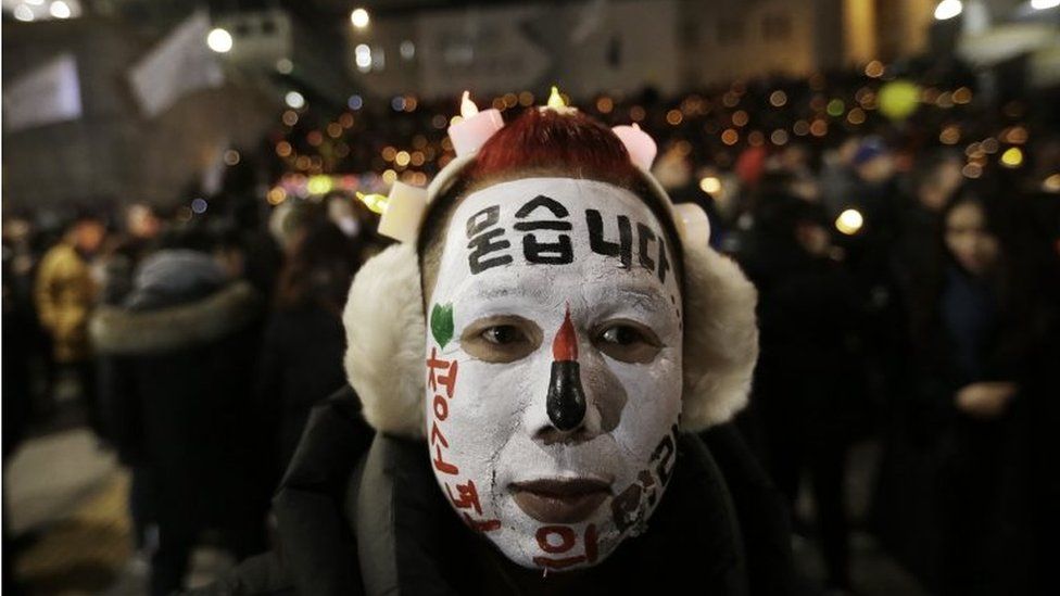 A protester with his face painted attends a candle light vigil calling for impeached President Park Geun-hye to step down in Seoul, South Korea, on 31 December 2016
