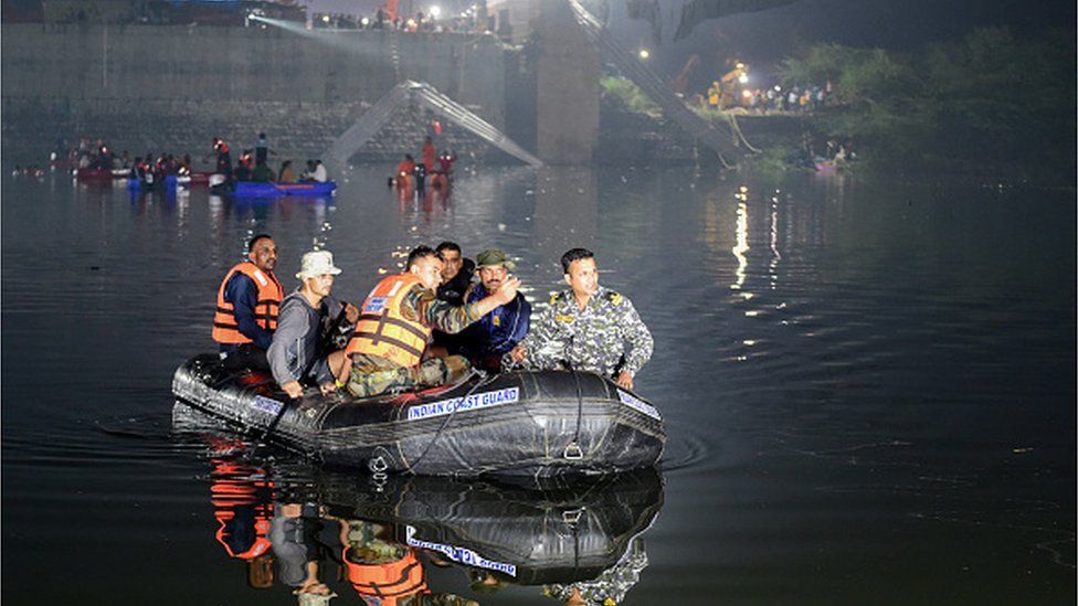 Индийские спасатели проводят поисковые работы после обрушения моста через реку Маччху в Морби, примерно в 220 км от Ахмадабада, рано утром 31 октября 2022 года.