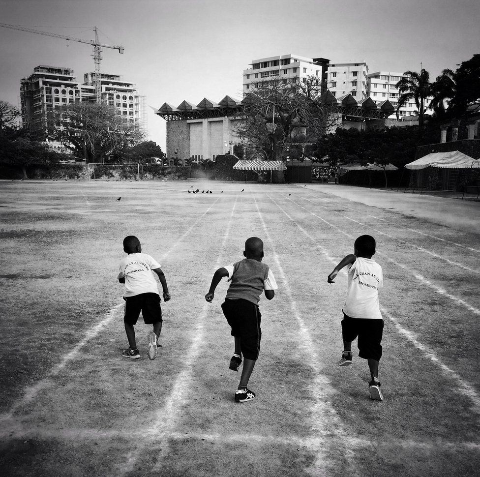 Three boys run on a school track