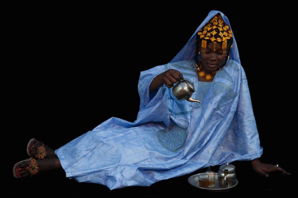 A newly wed woman in a striking blue dress pouring tea