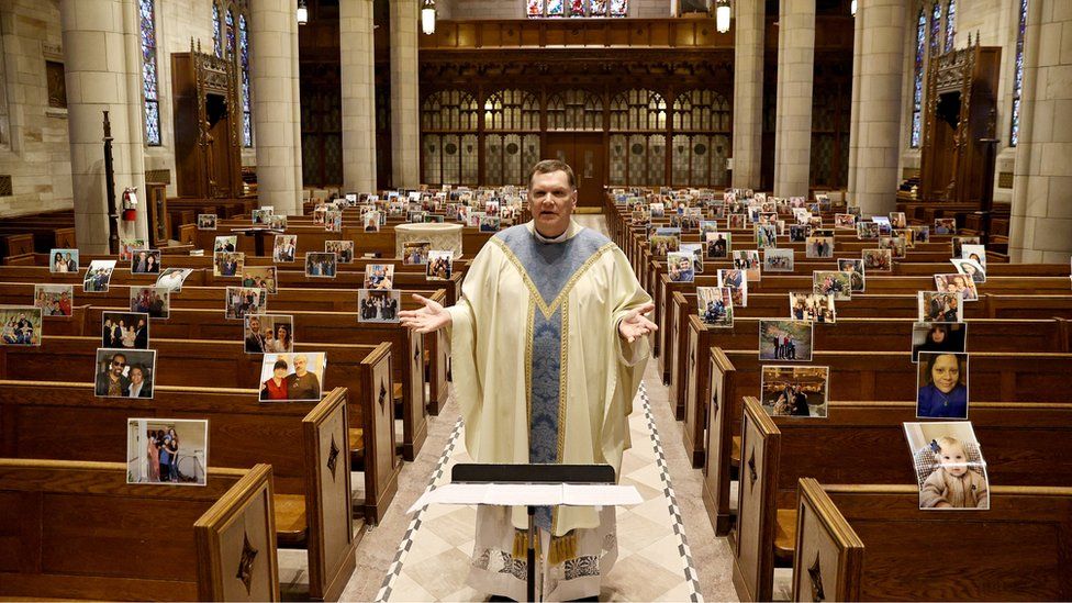 Rev Brian X Needles live-streams Easter Sunday Mass to picture print-outs sent in by parishioners and attached to pews by staff at Our Lady of Sorrows Catholic Church in South Orange, New Jersey, 12 April 2020