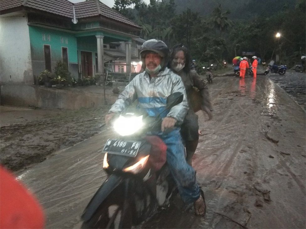People ride a motorbike on a road covered with volcanic ash after Mt Semeru erupted, pictured in Sumberwuluh village in Lumajang regency, East Java province, on 4 December, 2021