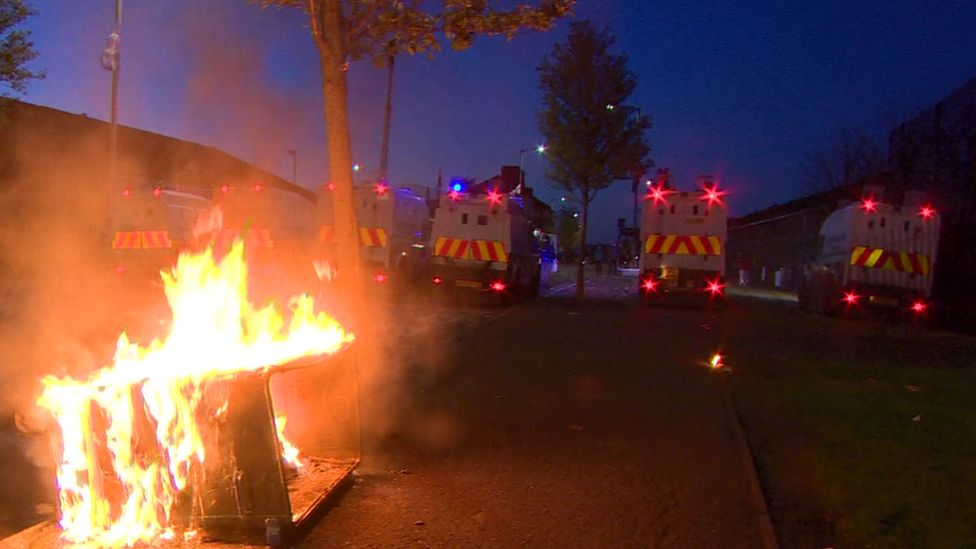 Police Land Rovers parked near a burning bin in Belfast