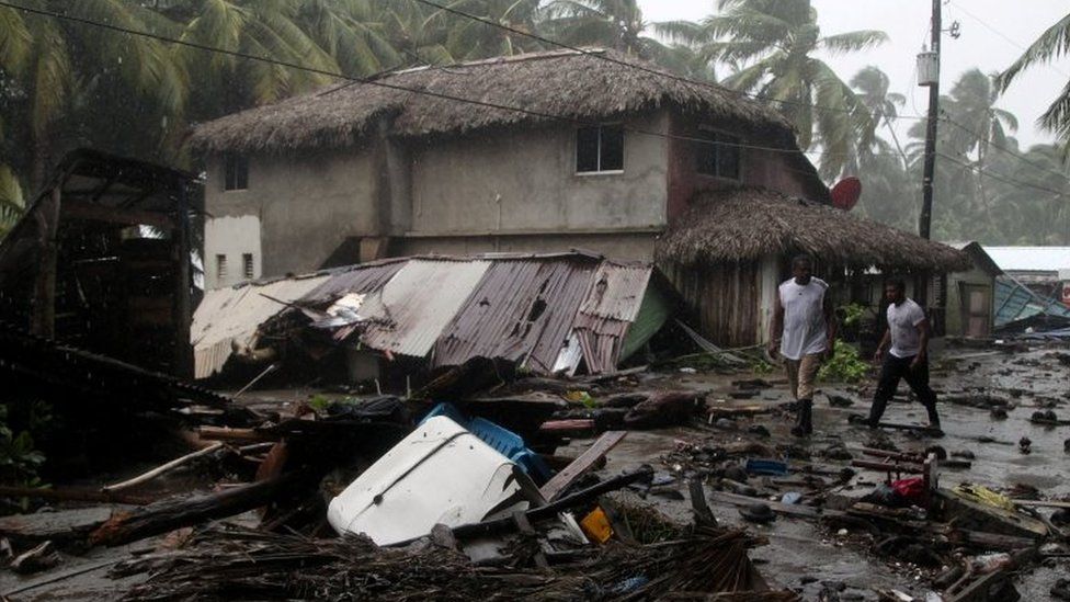 People walk past debris on the northern coast of the Dominican Republic