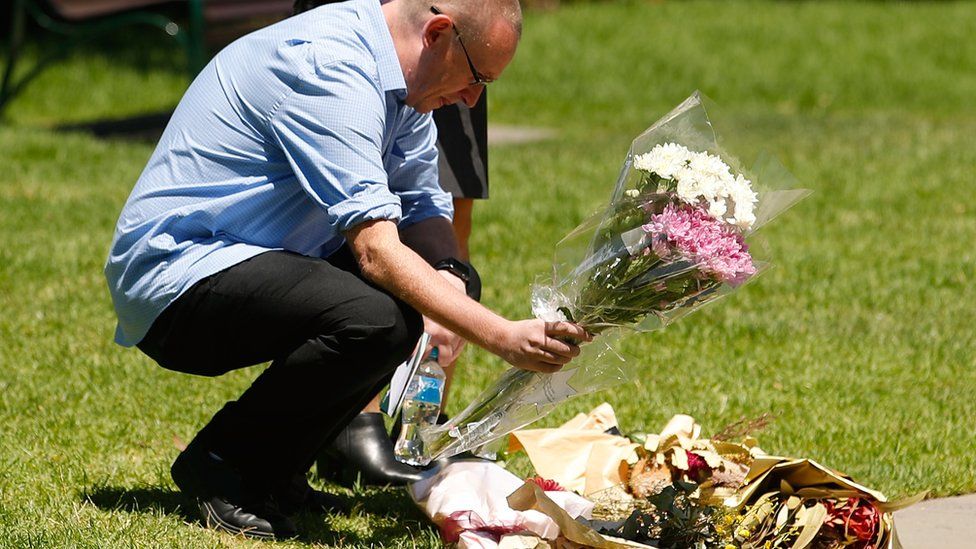 A man places flowers near a plaque honouring the victims of the incident