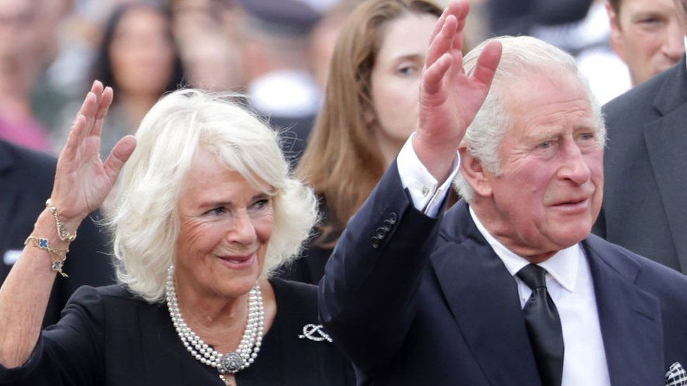 Queen Consort Camilla and King Charles III wave to crowds