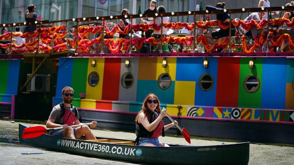 A couple enjoy the hot weather in a canoe on the canal in Paddington Basin, north London on Bank Holiday Monday