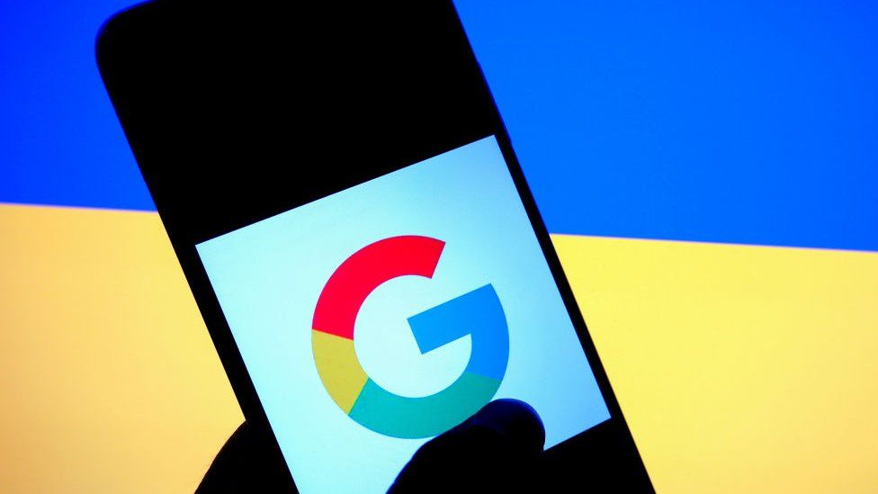 Логотип Google на смартфоне перед флагом Украины
