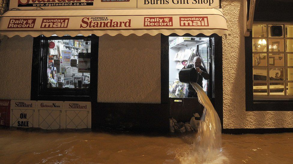 Shopkeeper Donald Irving bails floodwater out if his shop after the River Nith burst its banks in Dumfries