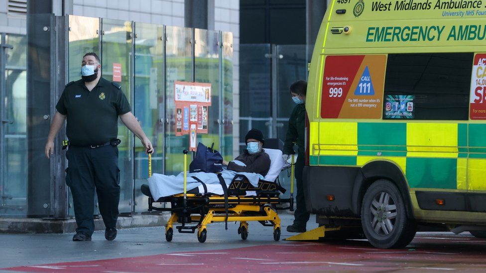 Health workers transport a patient outside the Queen Elizabeth Hospital Birmingham