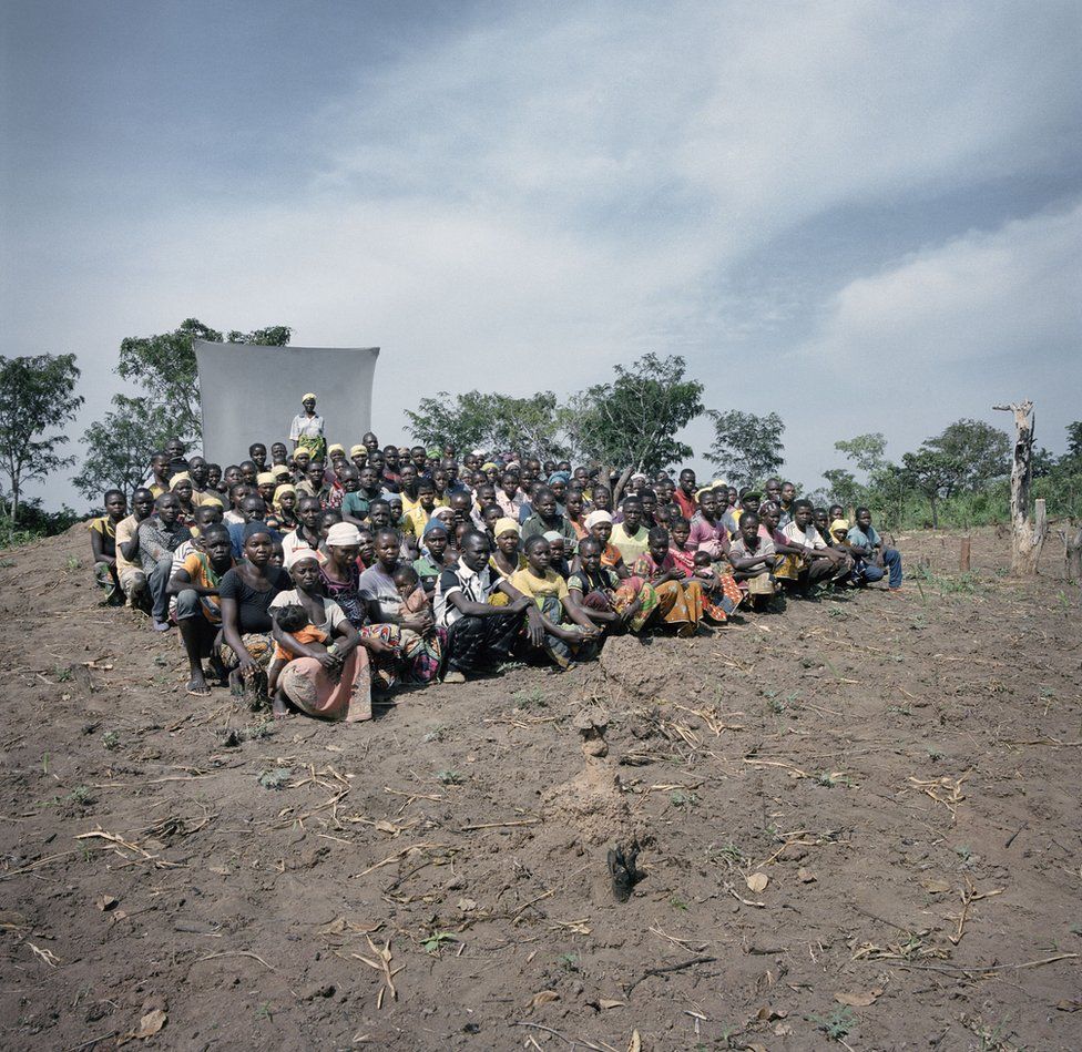 A group sit in a field.