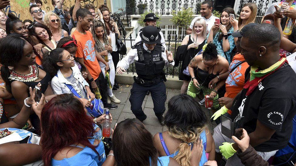 Revellers watch police officers at the Notting Hill Carnival