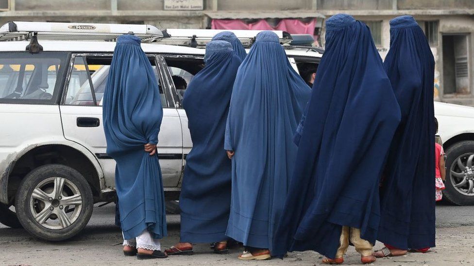 Women wearing a burqa wait to board into a local taxi in Kabul on 31 July 2021