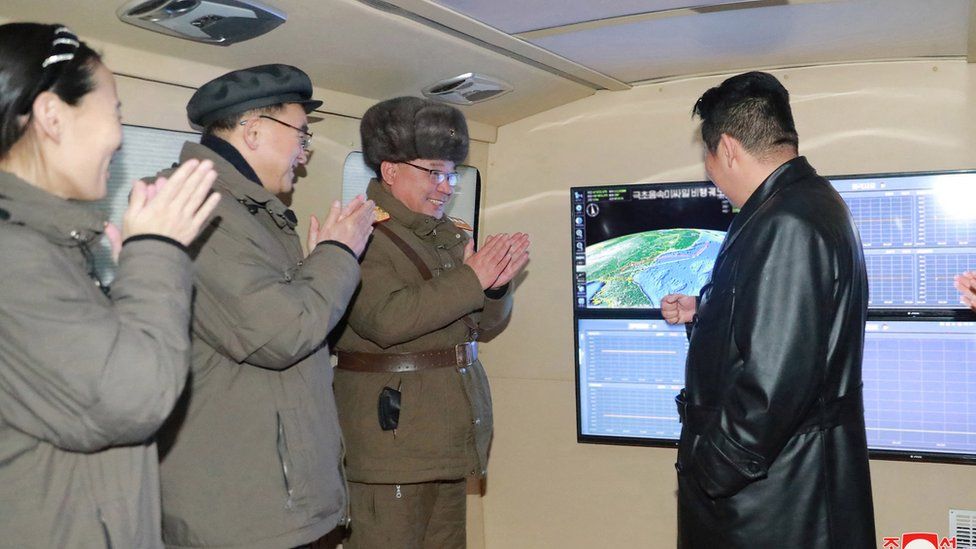 State media photo shows three officials clapping as Kim Jong Un watches what North Korea says was a successful hypersonic missile launch