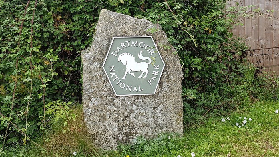 A stone with a sign saying "Dartmoor National Park"